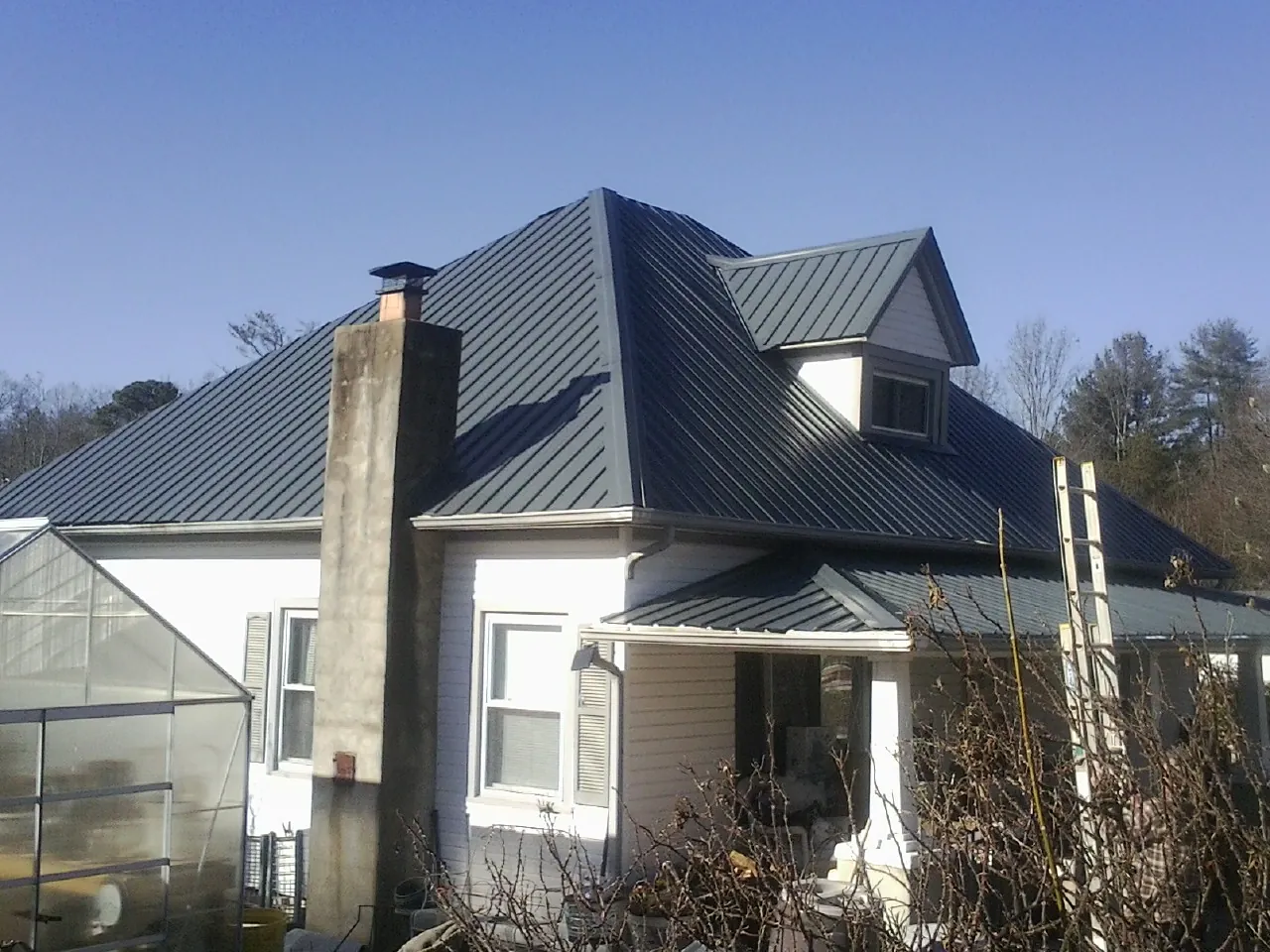 Dark blue standing seam metal roof on a white farmhouse with dormer — Slate & Tile Roof Repair by Roofing Brothers in Fall City