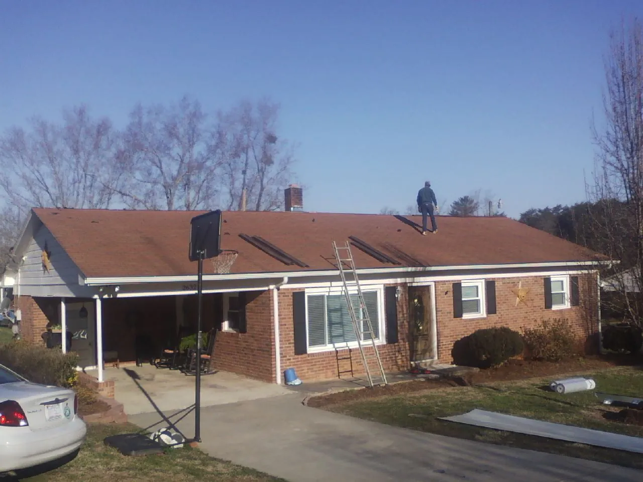 Roofer stripping a shingle roof on a brick ranch before metal panels in Fall City