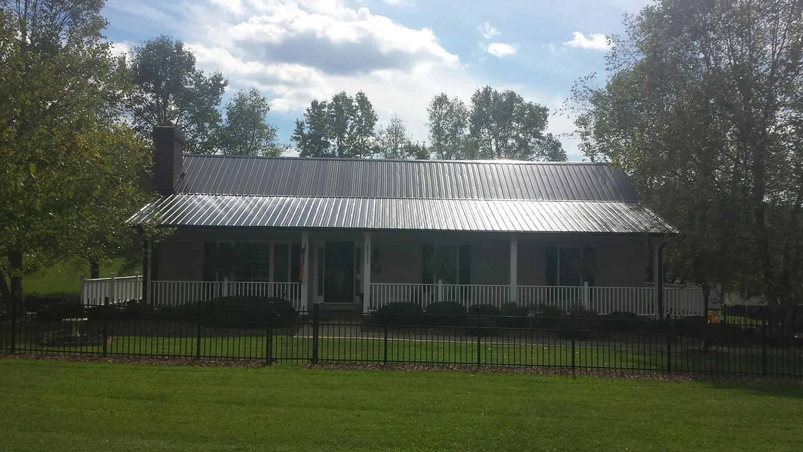 Gray metal roof on a brick ranch with a full width front porch — Gutter Guard Installation work by our crew in Fall City