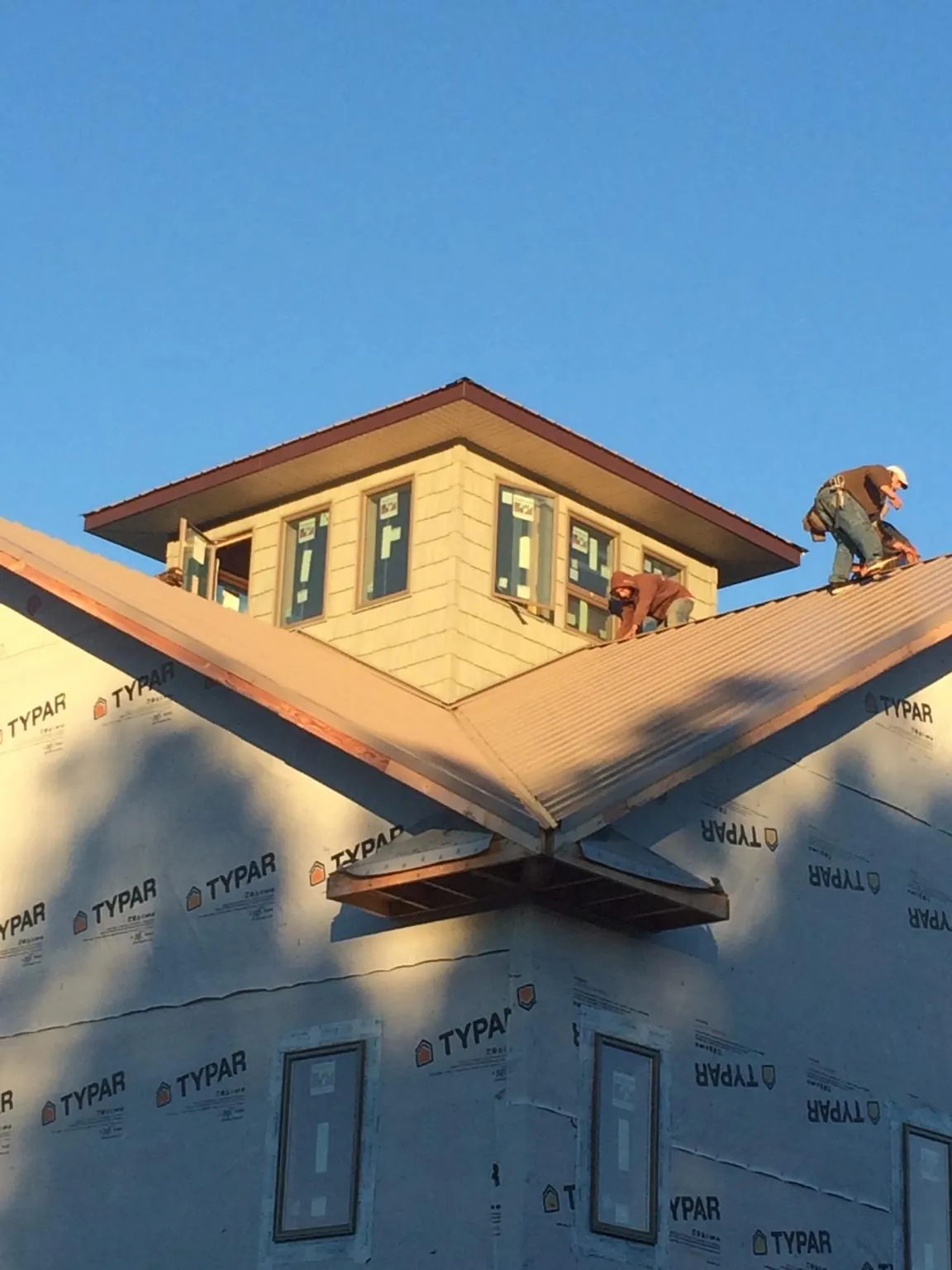Roofers working around a rooftop cupola on a new metal roof at sunset — Roof Waterproofing in Fall City by Roofing Brothers